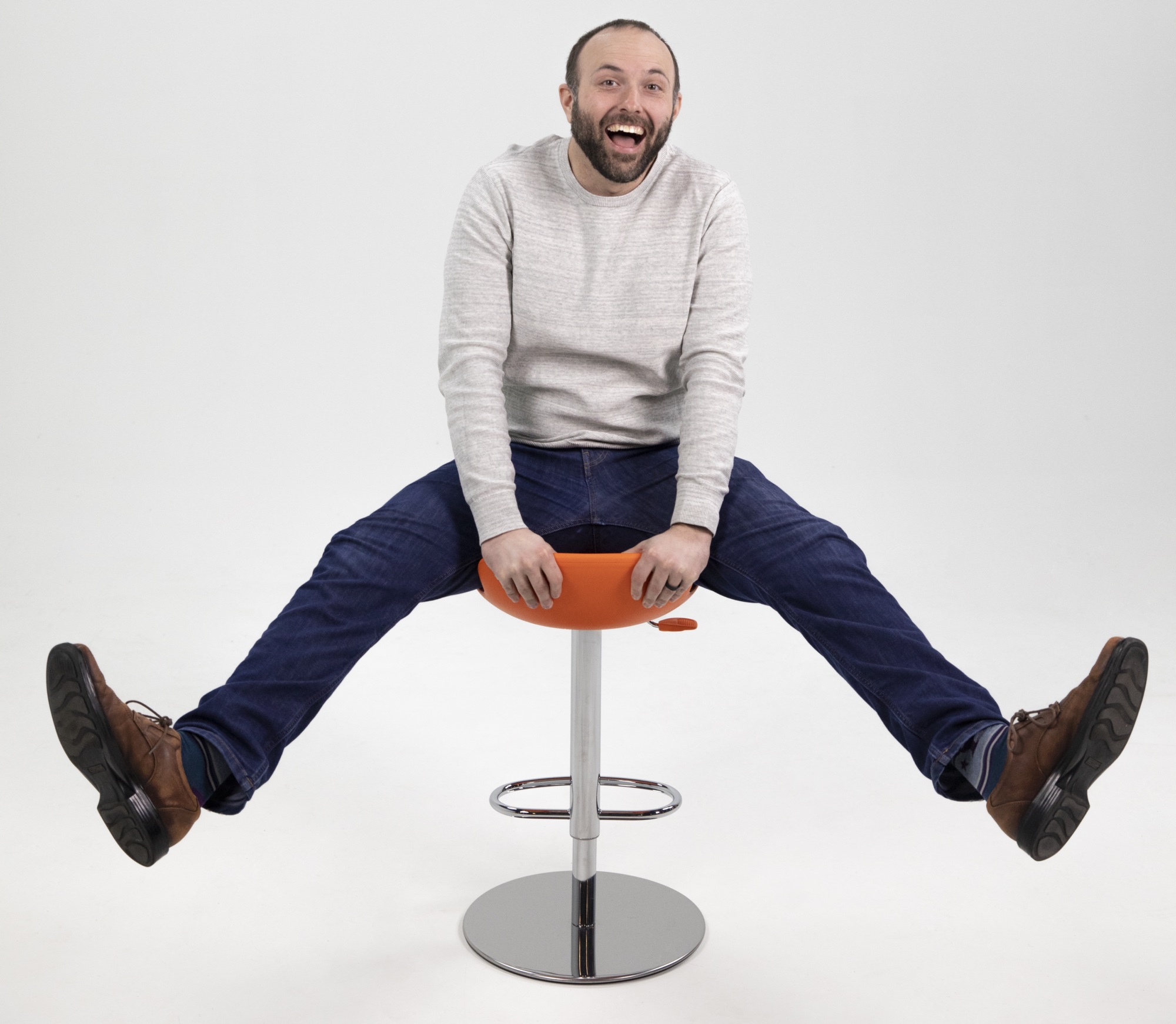 Tim straddling on a stool with a goofy facial expression